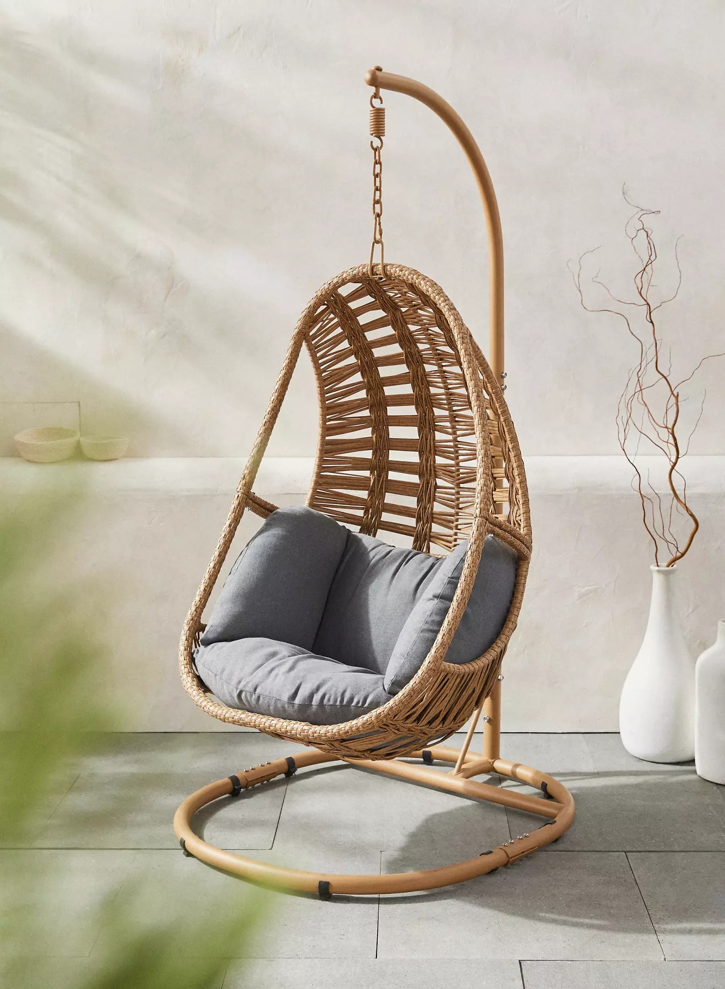 modern woven rattan egg chair suspended from hanging stand