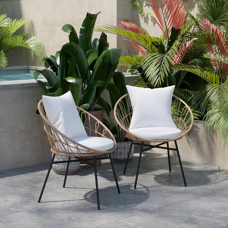 two round rattan outdoor chairs with white cushions