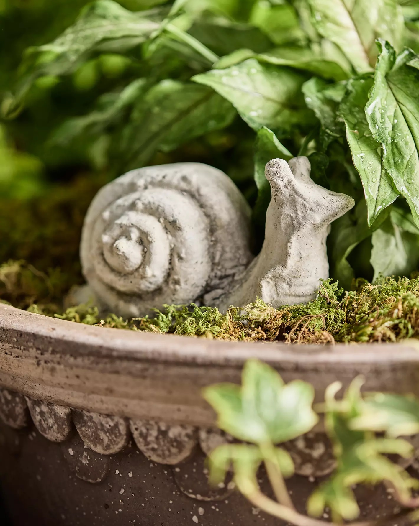 Miniature snail statue in a potted plant