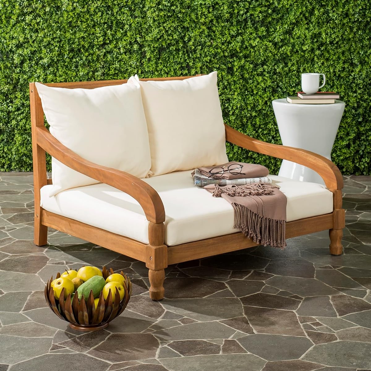 low wooden patio chair with white cushions and curved armrests