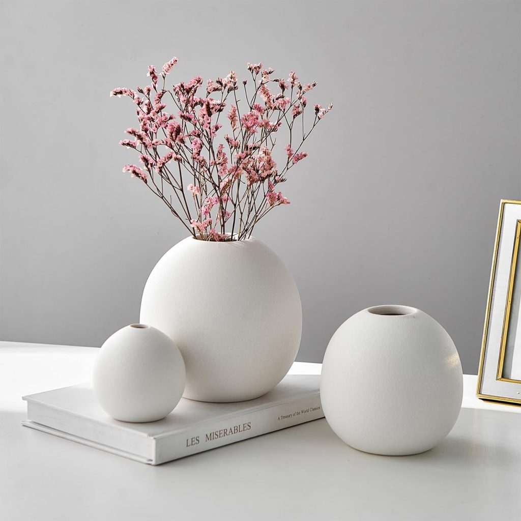 trio of textured white ceramic vases on table with pink flowers
