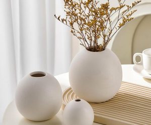 three white ceramic vases on table with dried yellow flowers